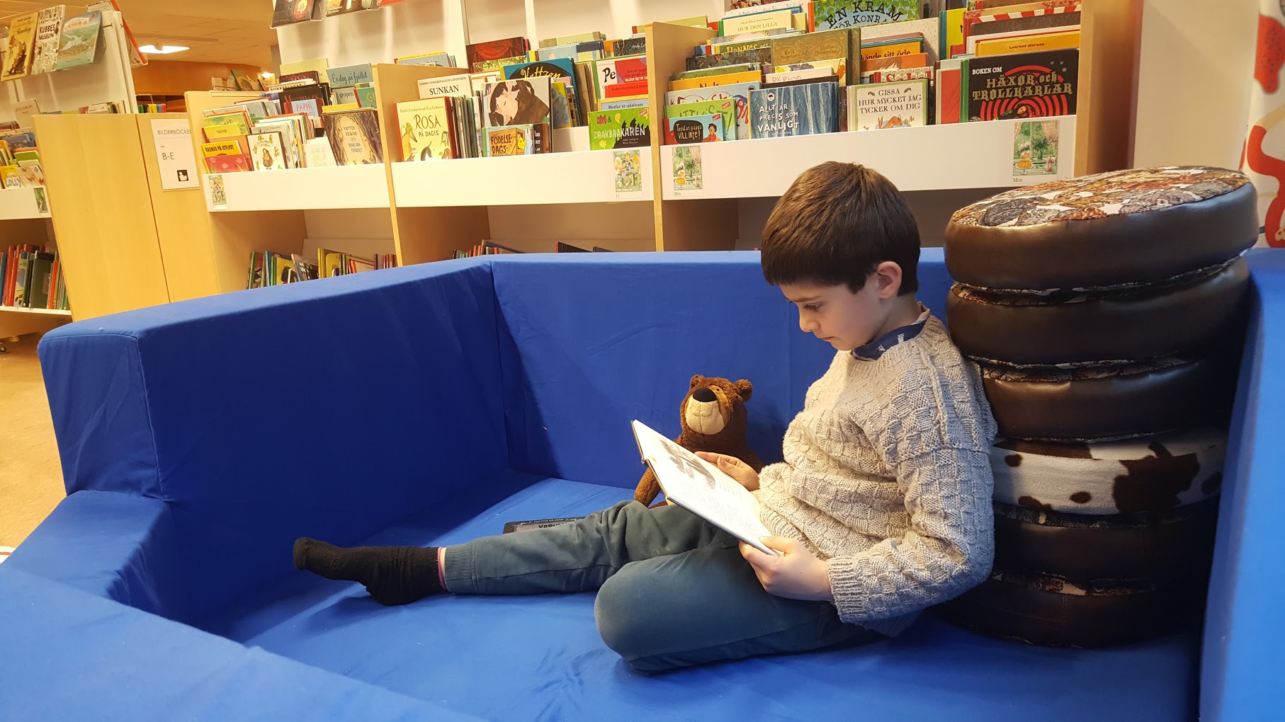 Pojke läser bok på biblioteket