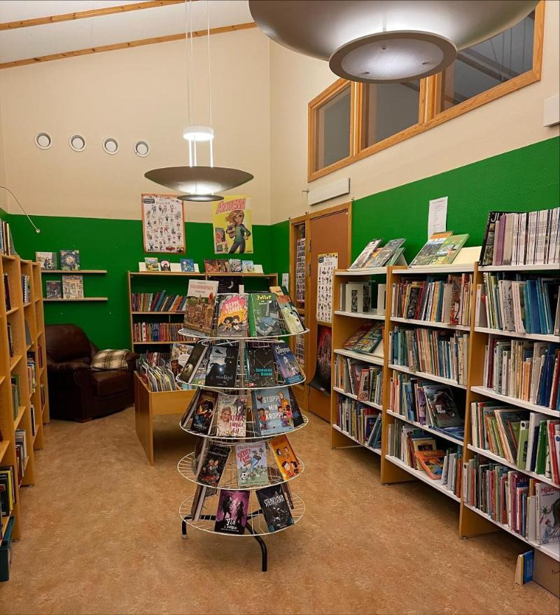 Ett litet trivsamt skolbibliotek med gröna väggar. 