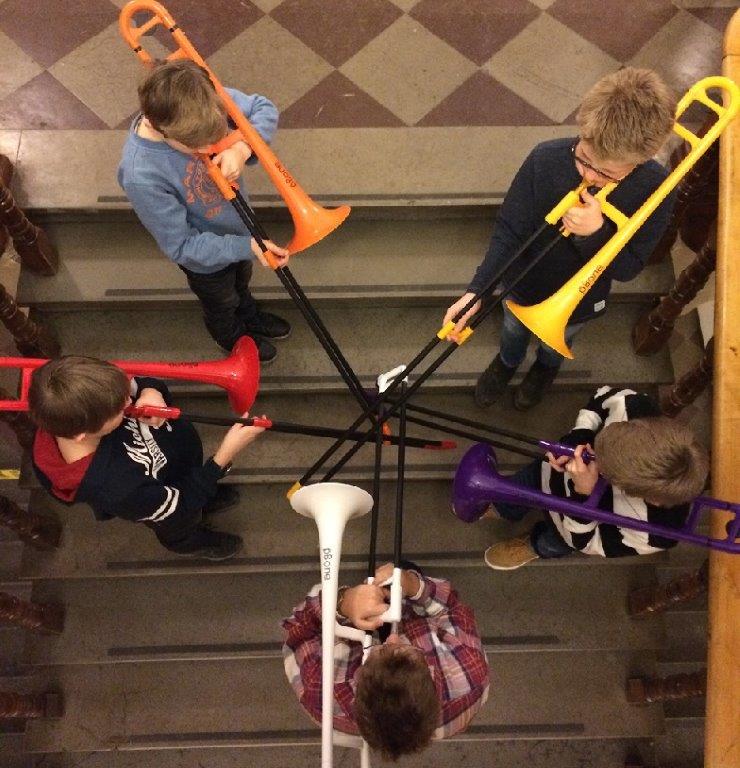 5 elever spelar på färgglada tromboner i en trappa.