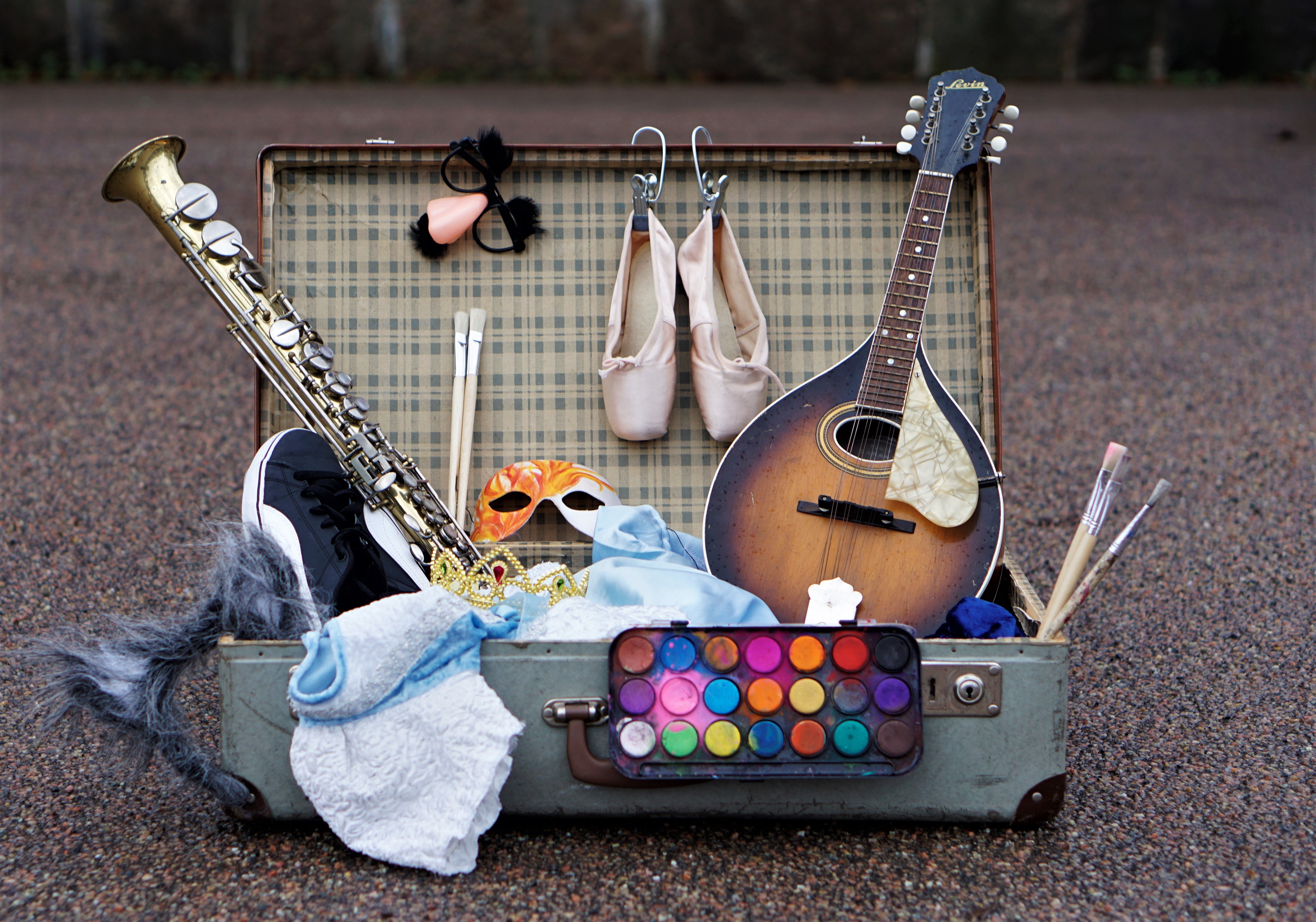 En koffert fylld med grejer som pensalar, ballettskor, unstrument och masker.
