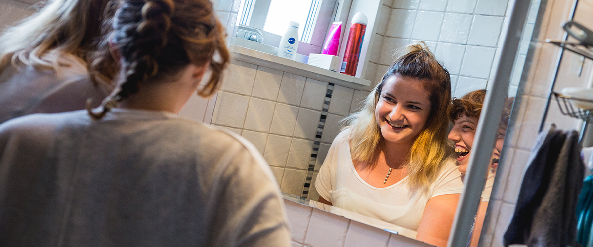 Kvinna som speglar sig och skrattar. Bredvid henne står personal från Uddevalla kommun. 