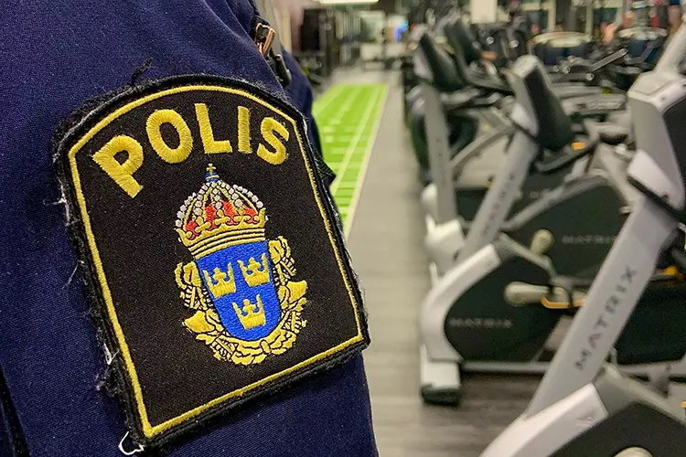 polismärke på en ärm och ett gym i bakgrunden