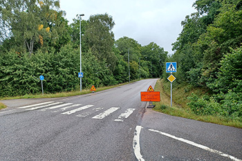 Skafterödsvägen är en asfalterad väg med skog och grönt på båda sidor här syns en orange skylt i backen upp