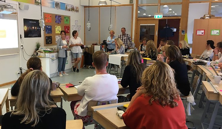 Representanter från Hälsokällan på besök i ett klassrum fullt av personal på Hogstorps skola.