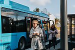 tre glada äldre kvinnor står intill en blå buss